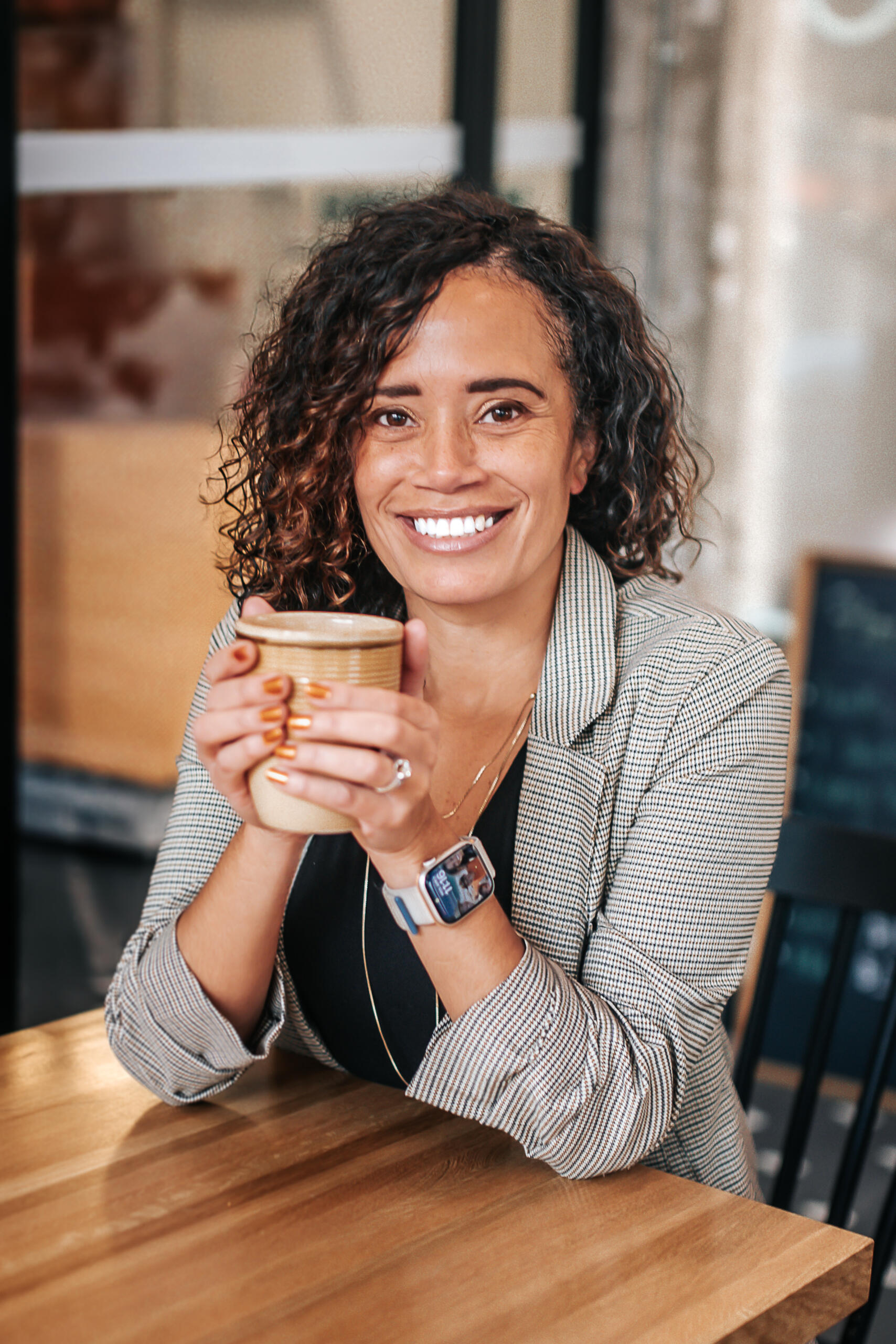 Photo of Amanda, smiling, with both hands wrapped around a coffee mug.